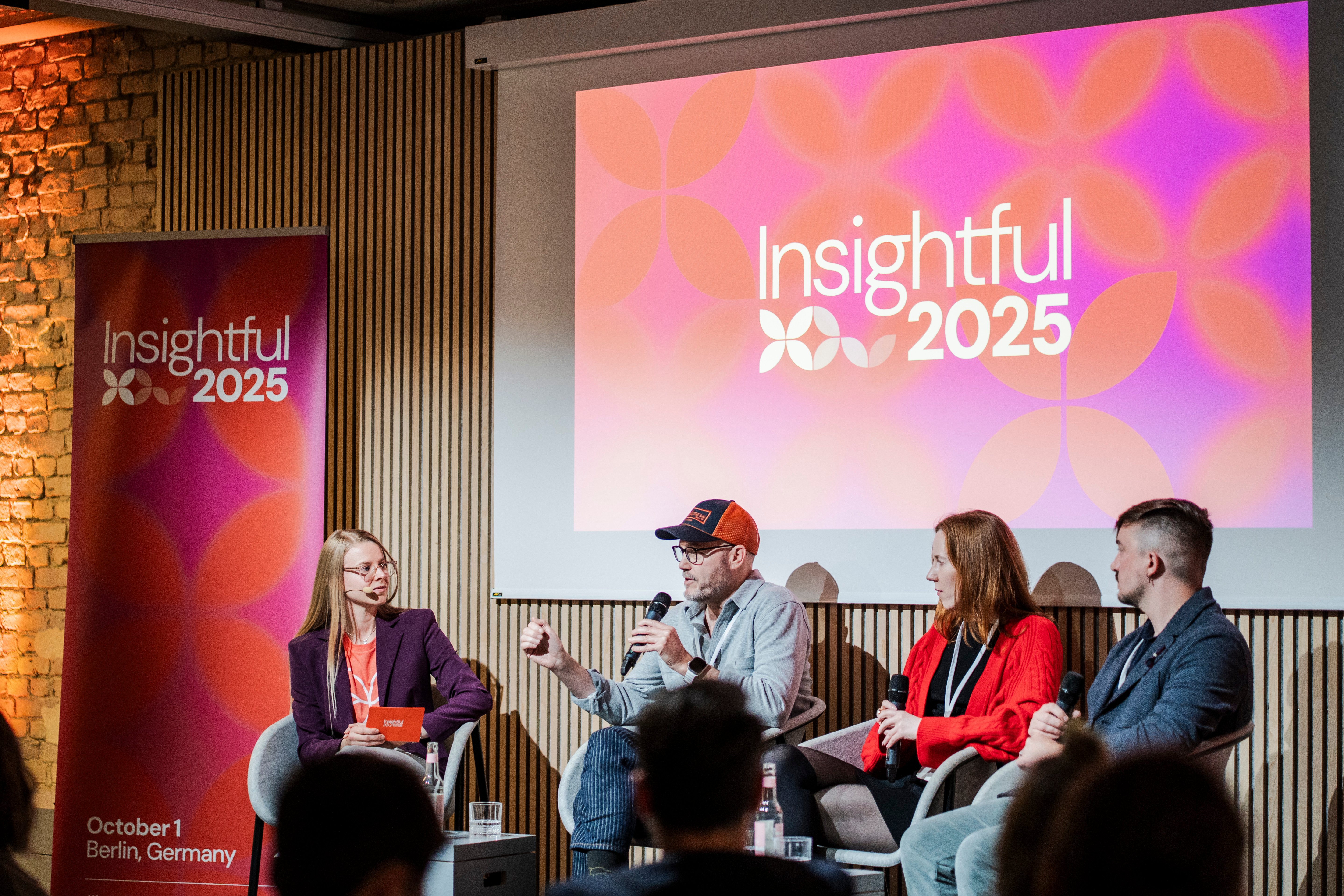 The Consumer Bahavior panle moderated by Hannah from PlaytestCloud. The panelists are seated on grey armchairs on the stage of Insightful 2025 with the Insightful logo behind them. From the right: Josh wearing a blue blazer, Galina wearing a red cardigan, Matt wearinf an orange and blue cap and a grey shirt, and Hannah wearing a purple blazer on top of the Insightful t-shirt in orange.