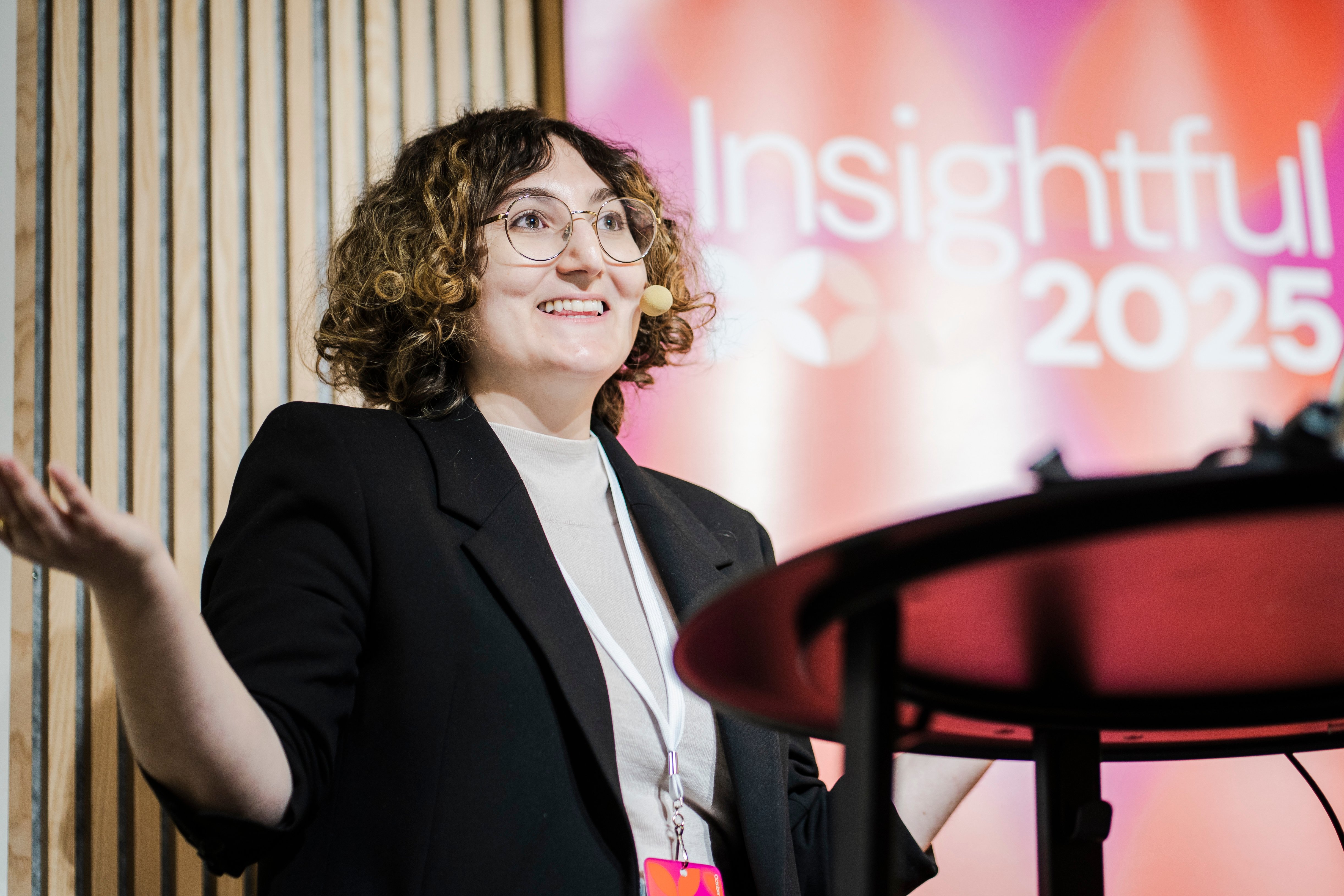 Natalie Gedeon from Netflix presenting on the stage of Insightful 2025. She is wearing a black blazer on top of a grey shirt. 
